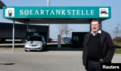 FILE - Juergen Silberzahn, mayor of Wolpertshausen, poses in front of a service station for electric cars powered by solar energy, in the village of Wolpertshausen near Schwaebisch Hall, Germany, March 18, 2016.