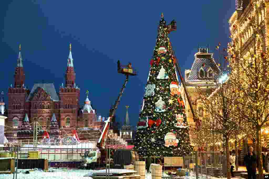 Municipal workers on cranes set up a Christmas tree in Red Square, with the Historical Museum, left, and the GUM State Department store, right, in the background, in Moscow, Russia.