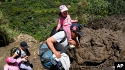 Residentes atraviesan un terreno que experimentó deslizamientos de tierra en Baños, Ecuador, el lunes 17 de junio de 2024.