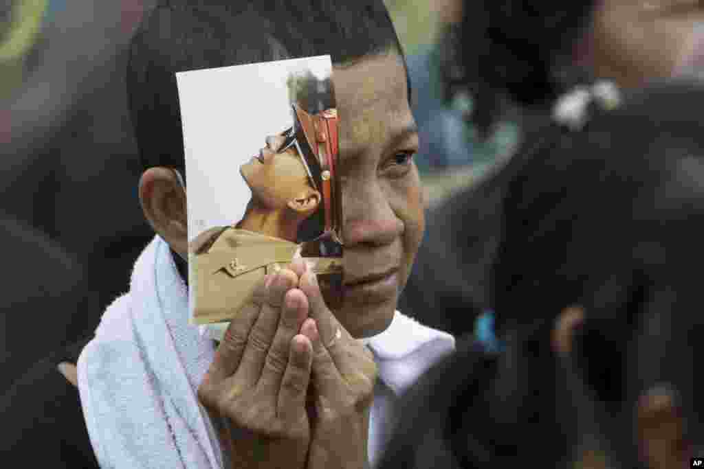 A mourner holds a portrait of the late King Bhumibol Adulyadej during his funeral procession and royal cremation ceremony in Bangkok, Thailand, Oct. 26, 2017.