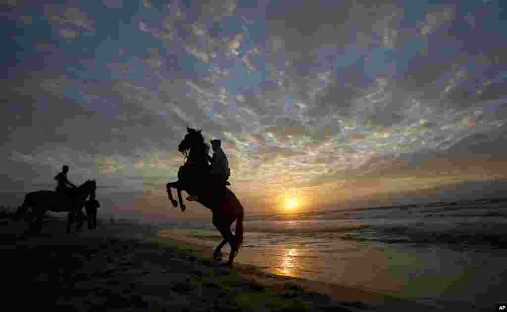 Palestinians rides horses on Gaza beach as the sun sets in Gaza City.