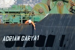 A crew member checks the new name of Iranian oil tanker Adrian Darya, formerly known as Grace 1, off the coast of Gibraltar, Aug. 18, 2019. Gibraltar rejected a U.S. demand to seize the tanker at the center of a diplomatic dispute.