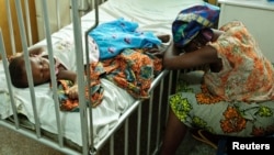 Hassana Ousmane rests her head against the bed where her 21-month-old daughter, Zeinab, suffering from malaria, rests at the Princess Marie Louise Children's Hospital in Accra, Ghana, April 25, 2012.