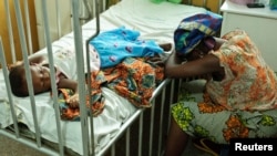 Hassana Ousmane rests her head against the bed where her 21-month-old daughter, Zeinab, suffering from malaria, rests at the Princess Marie Louise Children's Hospital in Accra, Ghana, April 25, 2012.