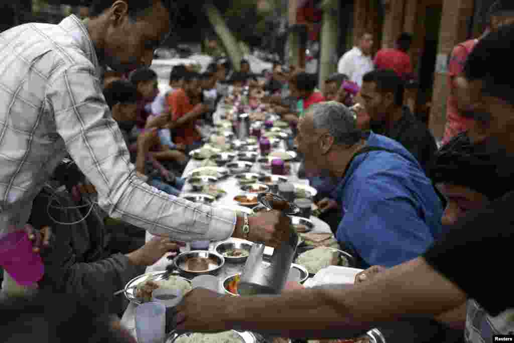 People break their fast, eating for free from charity tables on the street during the first day of the holy month of Ramadan, in Cairo, June 29, 2014. 