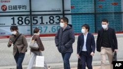 30일 일본 도쿄에서 증시가 하락한 것을 나타내는 전광판 앞으로 마스크를 착용한 시민들이 지나가고 있다. 