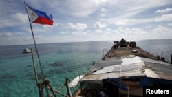 FILE - A Philippine flag flutters a dilapidated Philippine Navy ship that has been aground since 1999 and became a Philippine military detachment on the disputed Second Thomas Shoal, part of the Spratly Islands, in the South China Sea, March 29, 2014.