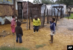 FILE - Children jump rope at the Tudor Shaft squatter settlement near Randfontein, west of Johannesburg, South Africa, Jan. 26, 2011.