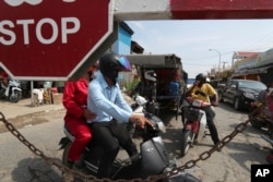 Residents are stopped near Phnom Penh International airport in Phnom Penh, Cambodia, Thursday, April 15, 2021. Cambodia’s leader on Wednesday said that the country's capital Phnom Penh will be locked down for two weeks following a sharp rise in COVID-19 cases.