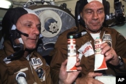 FILE - In the 1975 photo, astronauts Thomas P. Stafford, left, and Donald K. "Deke" Slayton hold containers of Soviet space food in the Soyuz Orbital Module during the joint Apollo-Soyuz Test Project docking mission.