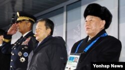 Lidè delegasyon Kore di Nò a nan Olenpyad Kore di Sid yo, Kim Yong Chol (adwat) ki t ap asiste seremoni fèmti a bò kote Prezidan Tribinal Konstitisyonèl Kore di Sid la, Lee Jin-sung (mitan), avèk kòmandan fòs militè ameriken yo nan Kore di Sid, Vincent Brooks (an inifòm militè, agoch).