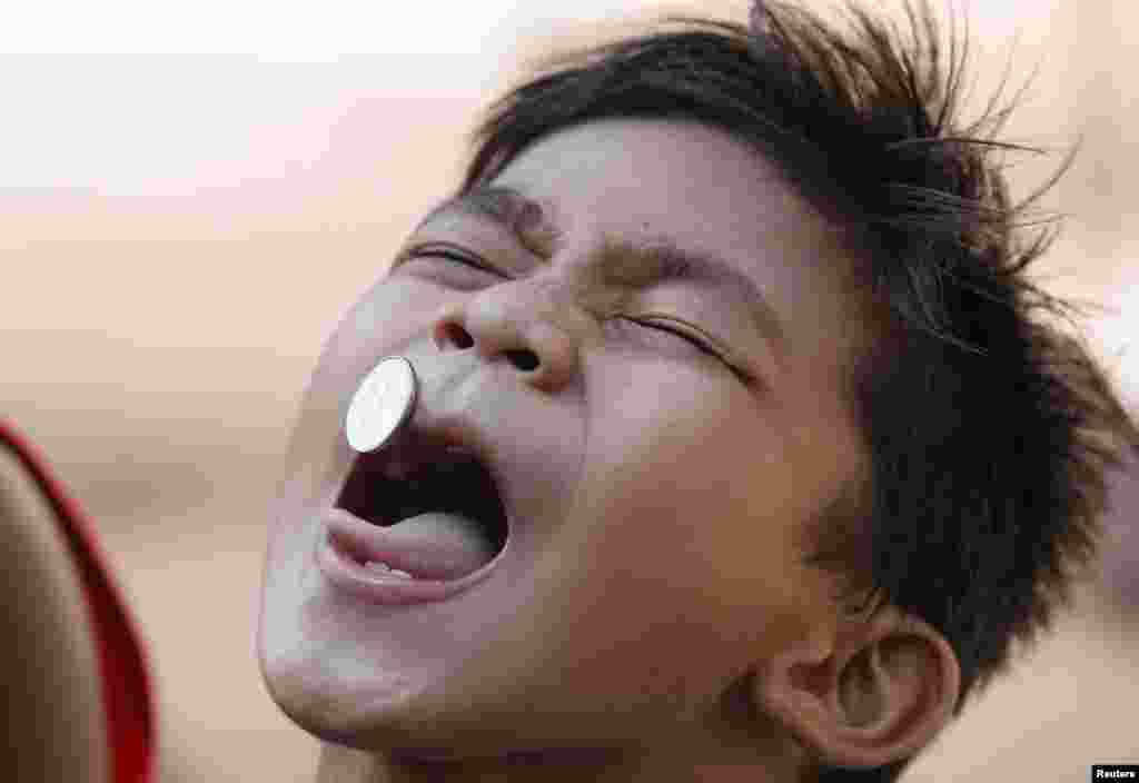 A boy navigates a coin on his face as he participates in parlour games organized by residents during feast day, in honor of their patron saint, Santa Rita De Casia, in Paranaque city, metro Manila, Philippines. The feast day of Santa Rita De Casia, which is celebrated on the third Sunday of the month of May, is observed by residents with colourful street dances and games.