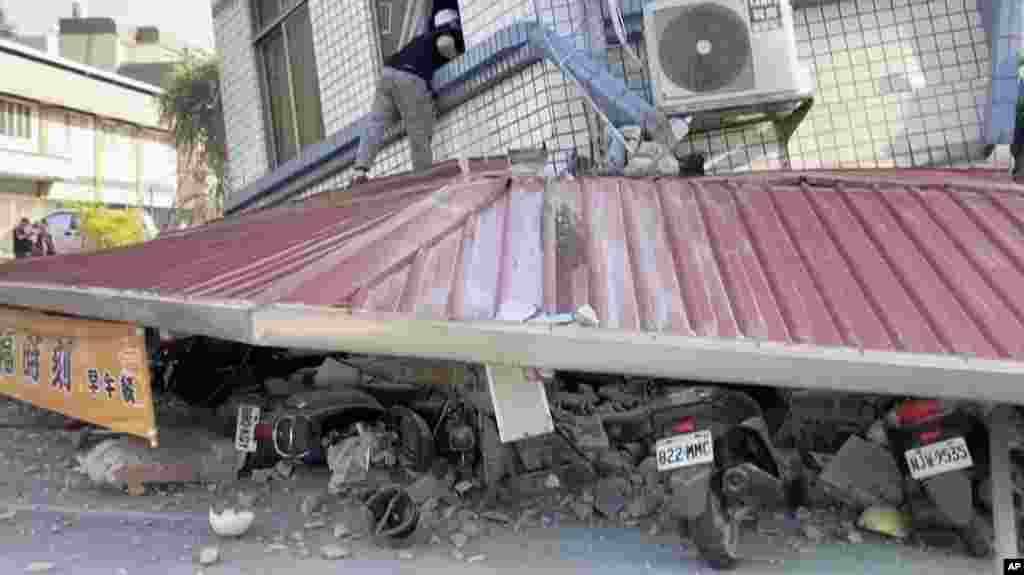 In this image taken from a video footage run by TVBS, a man checks a partially collapsed building in Hualien, eastern Taiwan, April 3, 2024.