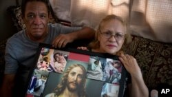 Juan Manuel González y María González Muñoz posan con una foto de Jesús y de su hermana Ramona, una mujer incapacitada de 59 años, quien murió de septicemia en Puerto Rico.