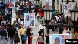 People walk past mayoral election campaign posters of Jorge Rodriguez from the United Socialist Party of Venezuela (PSUV) in Caracas, Dec. 4, 2013.