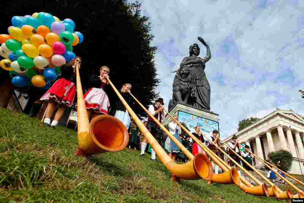 A Alphorn band in traditional Bavarian clothes play instruments during the traditional concert at the 182nd Oktoberfest in Munich, Germany.