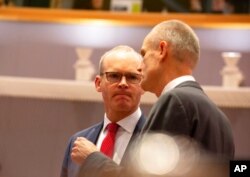 FILE - Irish Foreign Minister Simon Coveney, left, speaks with Dutch Foreign Minister Stef Blok during a meeting of EU foreign ministers at the Europa building in Brussels, Dec. 9, 2019.