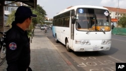 A Security guard stands at a bus stop as Phnom Penh begins its trial for public bus service, Wednesday, Feb. 5, 2014, in Phnom Penh, Cambodia. Phnom Penh launched the one-month pilot program with 10 air-conditioned buses traveling a single route with 36 stops through the city center. (AP Photo/Heng Sinith)