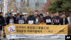 Victims of Japan's forced labor and their family members arrive at the Supreme Court in Seoul, South Korea, Nov. 29, 2018. The sign reads "Mitsubishi Heavy Industries must apologize and compensate victims."