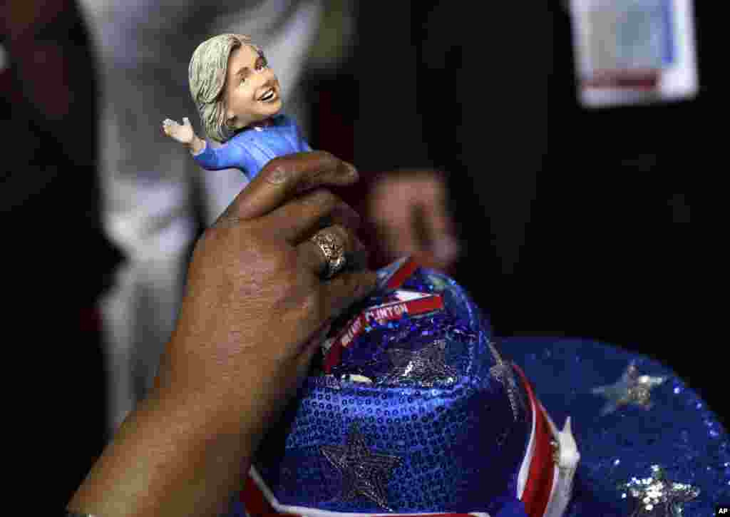A delegate adjusts a Hillary Clinton bubble-head doll on her head on the second day of the Democratic National Convention in Philadelphia.