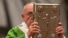FILE - Pope Francis hoists the Gospel book as he celebrates a mass in St. Peter's Basilica at the Vatican, Oct. 5, 2014, to open the extraordinary Synod on the family.