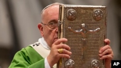 Pope Francis hoists the Gospel book as he celebrates a mass in St. Peter's Basilica at the Vatican, Oct. 5, 2014, to open the extraordinary Synod on the family.
