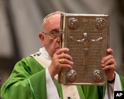 FILE - Pope Francis hoists the Gospel book as he celebrates a mass in St. Peter's Basilica at the Vatican, Oct. 5, 2014, to open the extraordinary Synod on the family.
