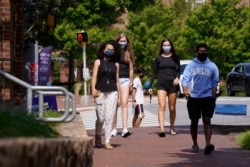 Students wear masks on campus at the University of North Carolina in Chapel Hill, N.C., Tuesday, Aug. 18, 2020. The university announced that it would cancel all in-person undergraduate learning starting on Wednesday following a cluster of COVID-19