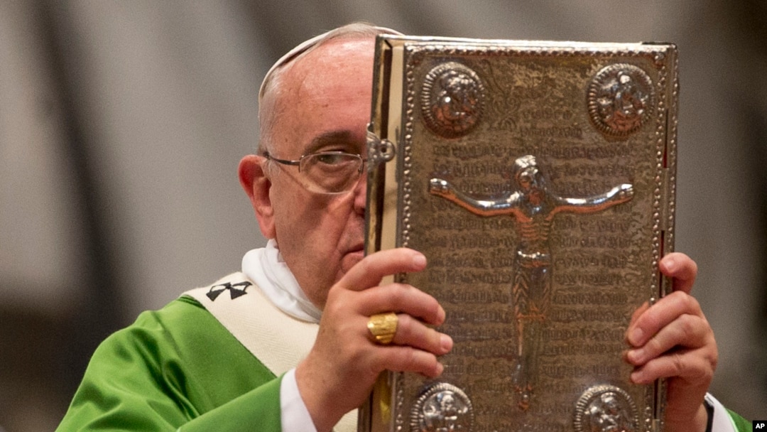 FILE - Pope Francis hoists the Gospel book as he celebrates a mass in St. Peter's Basilica at the Vatican, Oct. 5, 2014, to open the extraordinary Synod on the family.