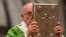FILE - Pope Francis hoists the Gospel book as he celebrates a mass in St. Peter's Basilica at the Vatican, Oct. 5, 2014, to open the extraordinary Synod on the family.