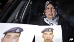 A woman holds a picture of her son, Jordanian pilot Lt. Mu'ath al-Kaseasbeh, who is held by Islamic State group militants, in Amman, Jordan, Jan. 27, 2015.