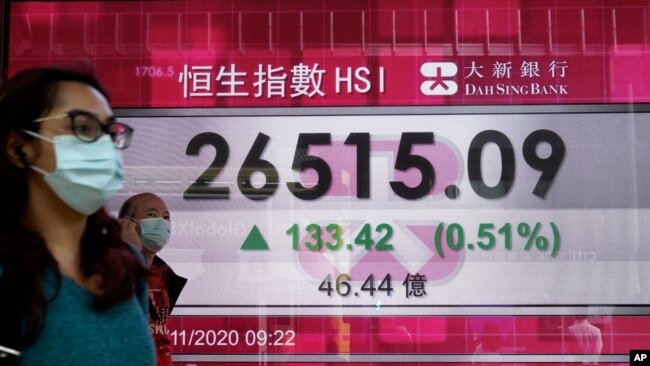 一个行人走过一家香港银行的电子广告牌。2020年11月17日,香港股指因新冠疫苗的不久可望面世而上扬。
