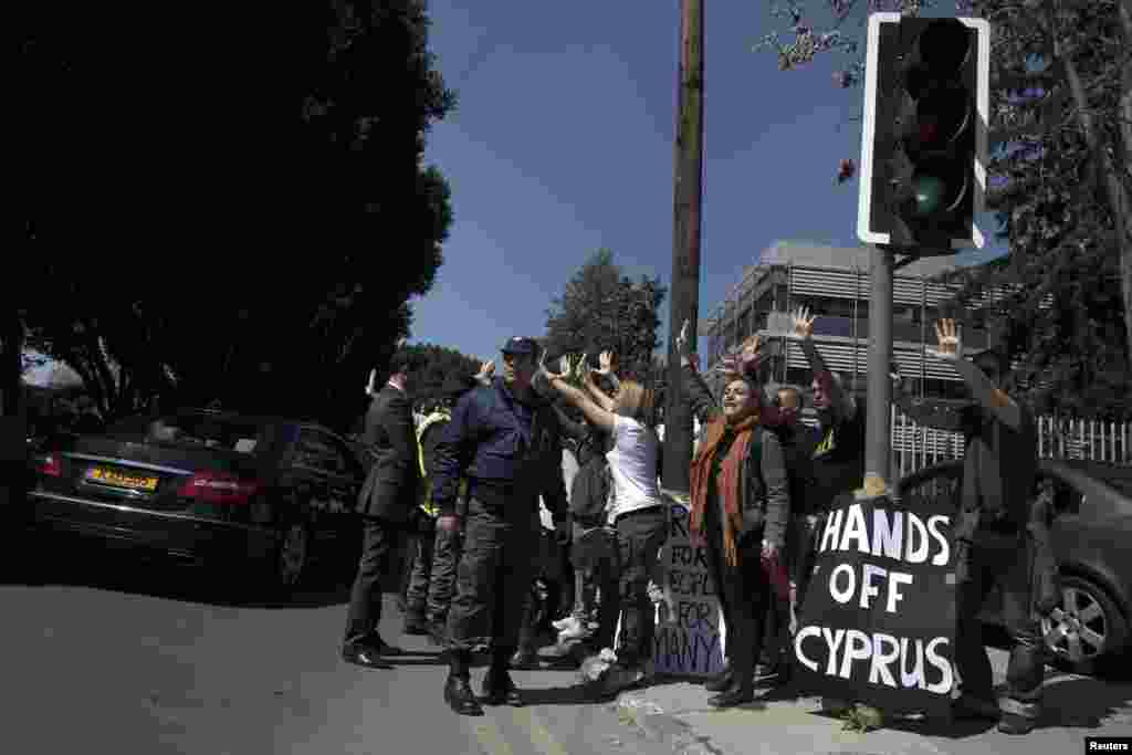 Demonstrators raise their arms in protest as Cypriot President Nicos Anastasiades's convoy drives to the parliament in Nicosia, Cyprus, March 18, 2013.