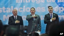Guatemalan President Jimmy Morales, center, sings the national anthem, during the inauguration of a soccer field in Mixco, Guatemala, Sept. 17, 2018. 