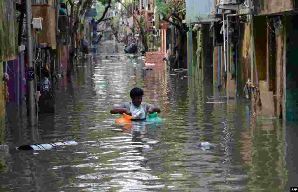 A man carries gas canisters through floodwaters on a street in Chennai, India. Thousands of rescuers are racing to evacuate victims of the Tamil Nadu flooding, which has claimed nearly 300 lives since Nov. 9.