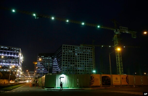 A Filipino worker checks his phone as he waits outside a construction site at a commercial area in suburban Pasay, south of Manila, Philippines, May 19, 2016. The Philippine economy grew faster than expected at 6.9 percent in the first quarter from the same period a year ago.