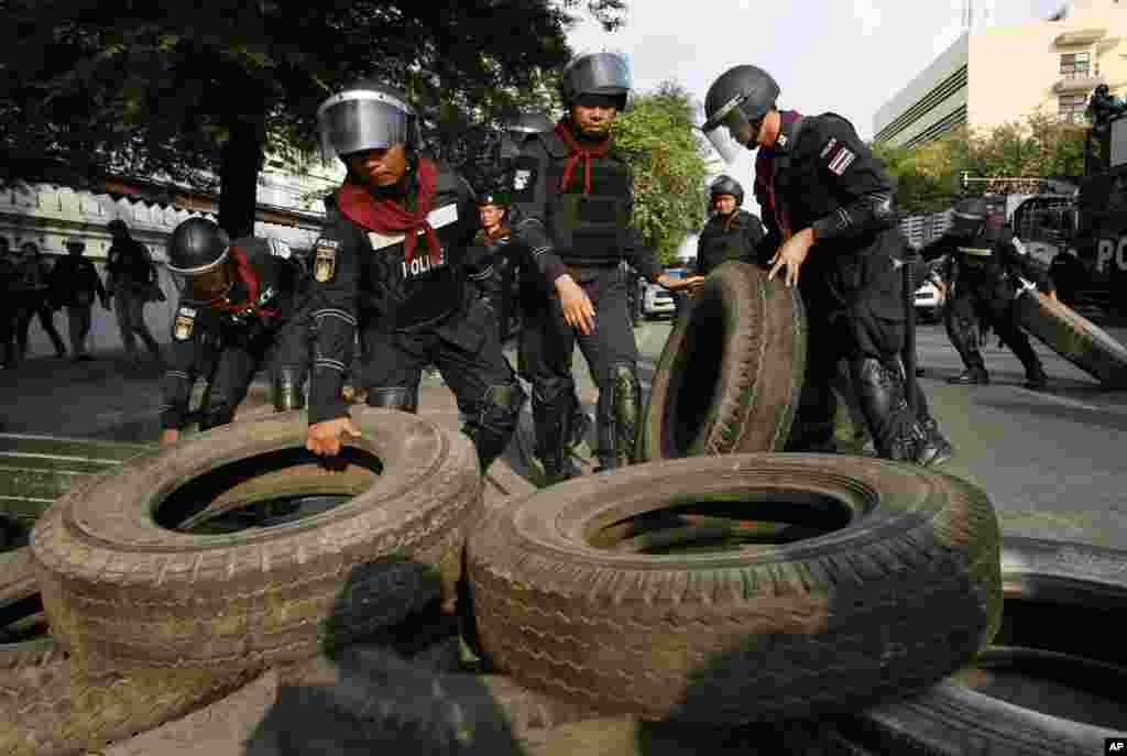 Polisi anti huru-hara memindahkan ban dan barikade lain yang dipasang oleh para demonstran anti-pemerintah di Bangkok (14/2). (AP/Wally Santana)