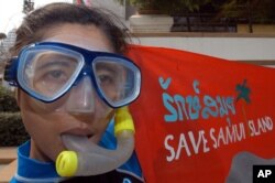 FILE - A Thai activist from Greenpeace holds a banner in protest of toxic pollution of Samui Island in front of the Tourism Authority of Thailand in Bangkok, March 8, 2005.
