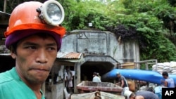 FILE - A mine worker watches the ongoing recovery operation after an explosion inside the tunnel in a collapsed gold mine in Mt. Diwata in Compostela Valley province, Philippines.