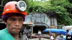 FILE - A mine worker watches the ongoing recovery operation after an explosion inside the tunnel in a collapsed gold mine in Mt. Diwata in Compostela Valley province, Philippines.