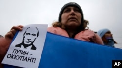 A woman holds a banner that reads: "Putin is Occupier" during a rally against the breakup of the country in Simferopol, Crimea, Ukraine, March 11, 2014. 