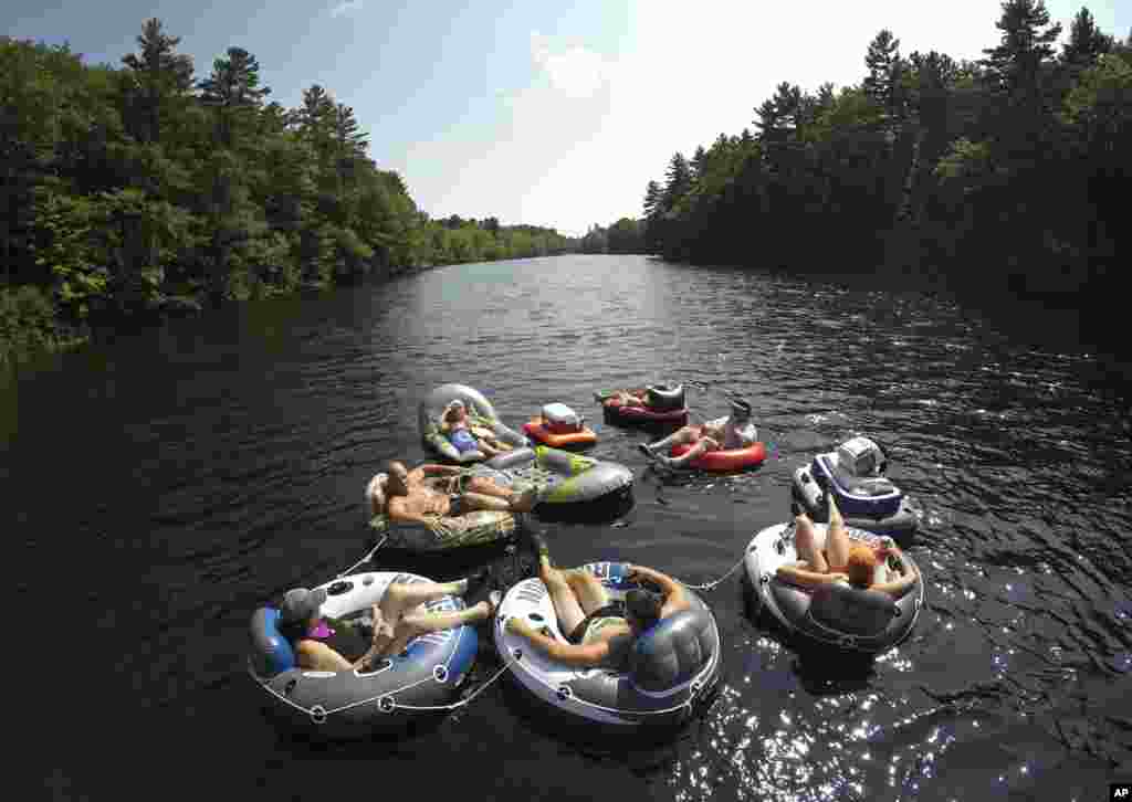 A flotilla of friends from Biddeford, Maine, raft down the Saco River at Bar Mills in Buxton, Maine, Aug. 26, 2018.