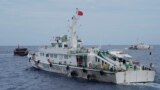 FILE - A Chinese coast guard ship tries to block the way of a Philippine supply boat, left, as it heads towards Second Thomas Shoal, at the disputed South China Sea on Aug. 22, 2023. Philippine officials on Sept. 25 condemned a floating barrier laid by Chinese vessels