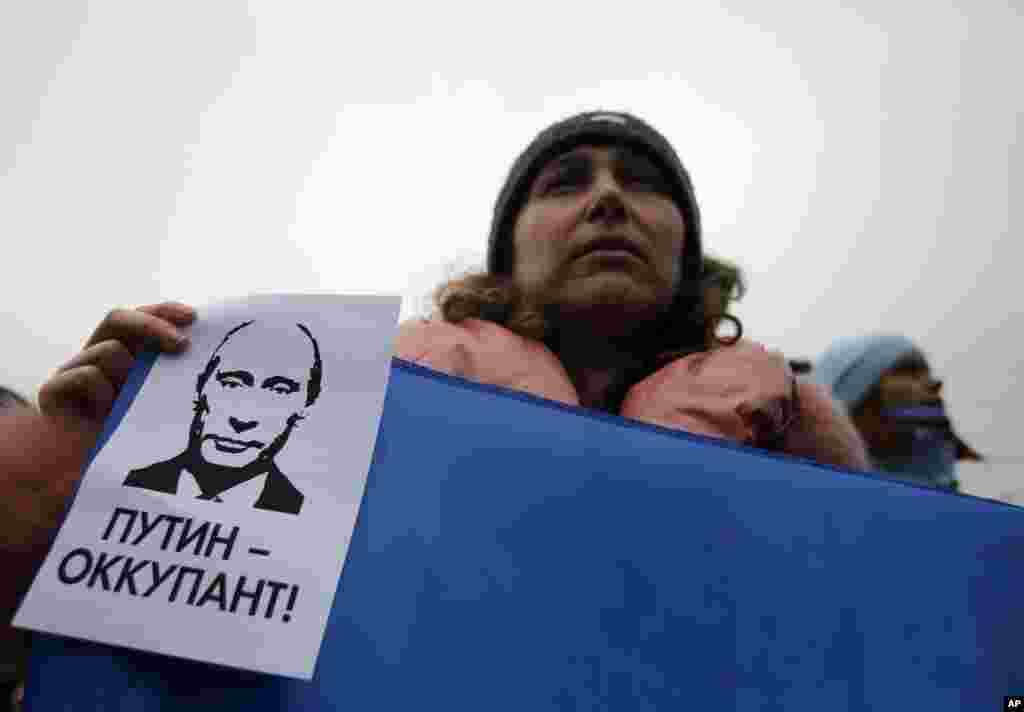 Seorang perempuan memegang banner yang bertuliskan: &quot;Putin adalah penjajah&quot; dalam sebuah protes menentang pecahnya Ukraina di Simferopol, Krimea, Ukraina, 11 Maret 2014. 