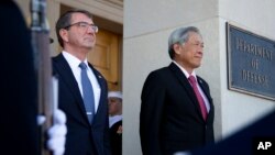 Secretary of Defense Ash Carter and Singapore's Minister of Defense Ng Eng Hen, listen as the national anthem of Singapore and the United States are played during an honor cordon at the Pentagon, Dec. 7, 2015. 