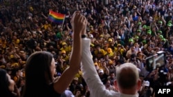 El candidato presidencial opositor Edmundo Gonzalez Urrutia levanta su mano junto a la de la dirigente María Corina Machado, durante un acto en la Universidad Central de Caracas, el 14 de julio de 2024.