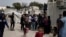 FILE - Migrants and refugees wait outside UNHCR offices for their papers, inside the camp of Moria on Lesbos, Greece.