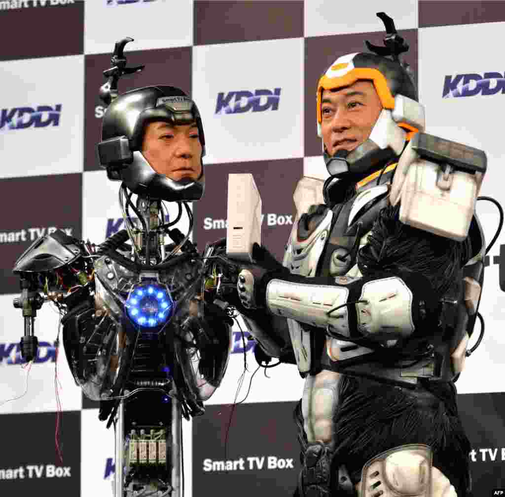 Aktor Jepang Ken Matsudaira (kanan), dengan pakaian robot melakukan presentasi di depan pers bersama robot android (kiri) di Tokyo. Robot android ini dikembangkan oleh perusahaan telekom Jepang, KDDI.