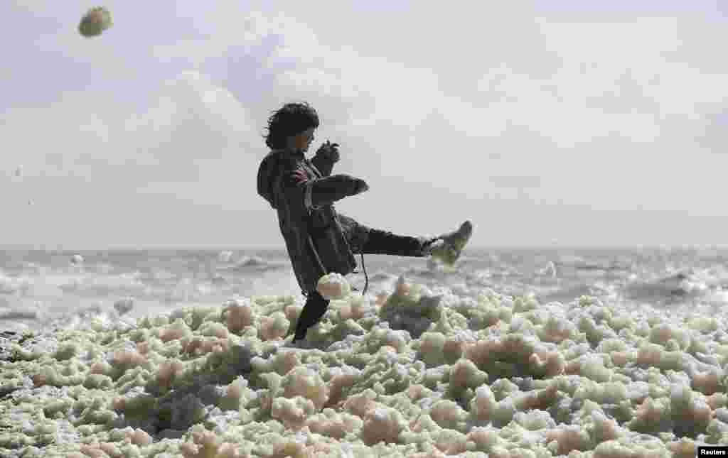 Max Butler-Cole, aged 9, plays in foam during stormy weather at Newhaven beach in southern Britain.