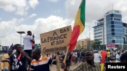 Opposition supporters react to the news of a possible mutiny of soldiers in the military base in Kati, outside the capital Bamako, at Independence Square in Bamako, Mali, Aug. 18, 2020. 